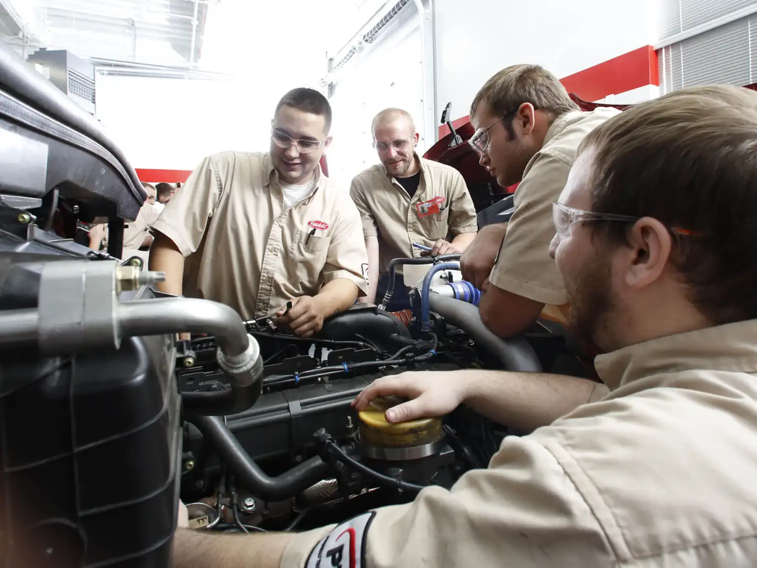 Group of technicians talking around an engine
